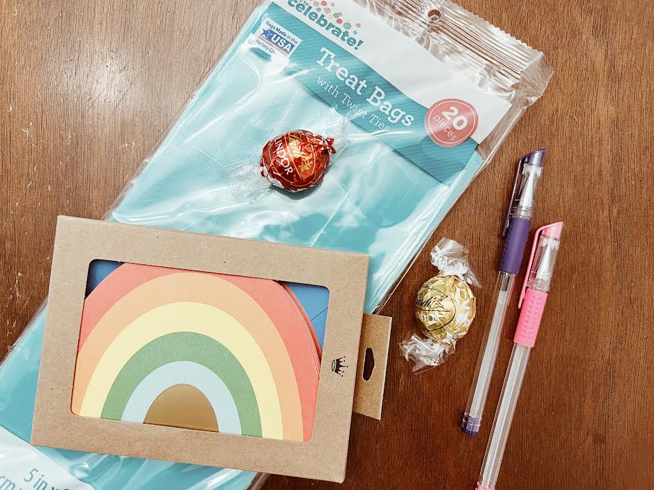 teacher appreciation gift ideas laid on table are treat bags, thank you cards, pens and chocolate