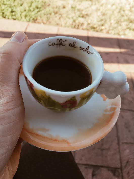 holding a cup of coffee outside on a sunny day