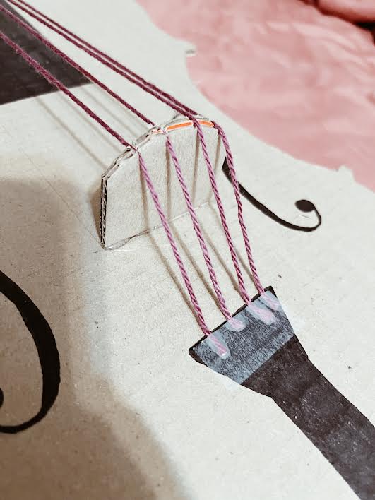 cardboard cello with bridge and yarn for strings