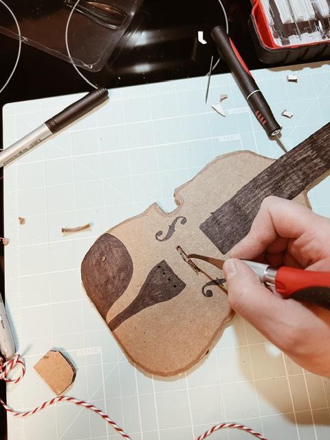 step 3 of diy cardboard viola is cutting out space for bridge