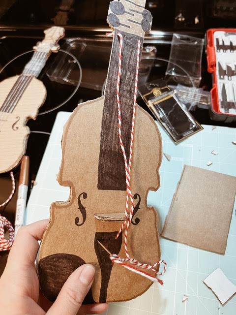 step 4 of cardboard diy viola is putting on strings