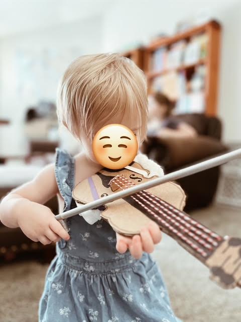 child playing diy cardboard viola